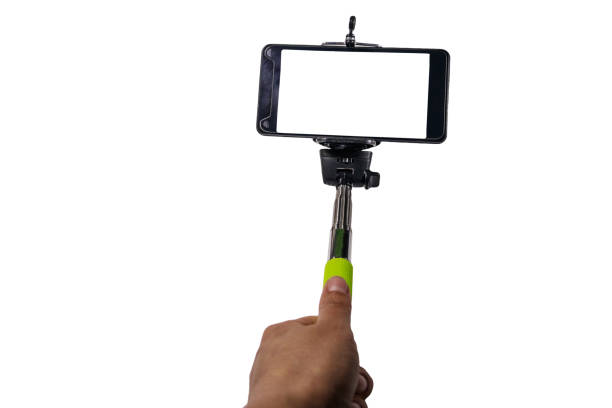 istock Human hand holding monopod for selfie with smartphone isolated on white background 947141352