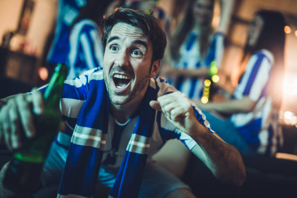 istock Young man encouraging his team while watching a match on TV at home. 947141616