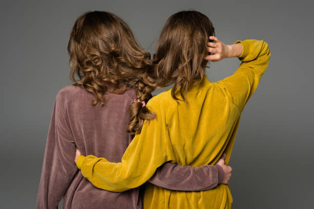 istock back view of twins hugging with hair in one braid isolated on grey 947146536