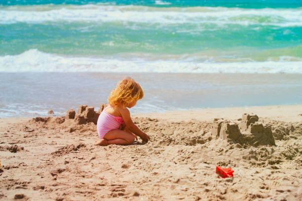 istock cute little girl play with sand on beach 947148078