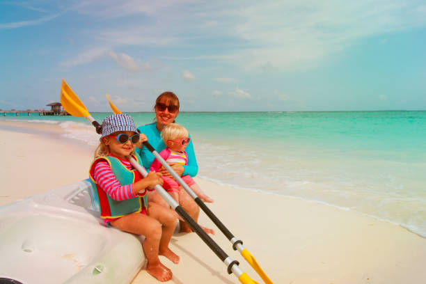 istock happy mother with kids kayaking at beach 947148598