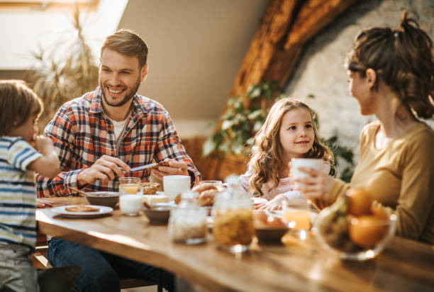 istock Young happy parents talking to their kids during breakfast time at dining table. 947149144