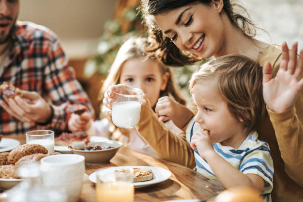 No mommy, I don't want to drink yogurt! Young family having breakfast at home while woman is giving her small son a glass of milk and he is refusing it. yogurt photos stock pictures, royalty-free photos & images