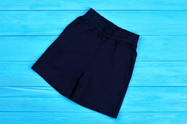 Dark blue cotton shorts for baby-boy. Textile short pants for little boys on blue wooden background. Trendy children shorts for casual wear.