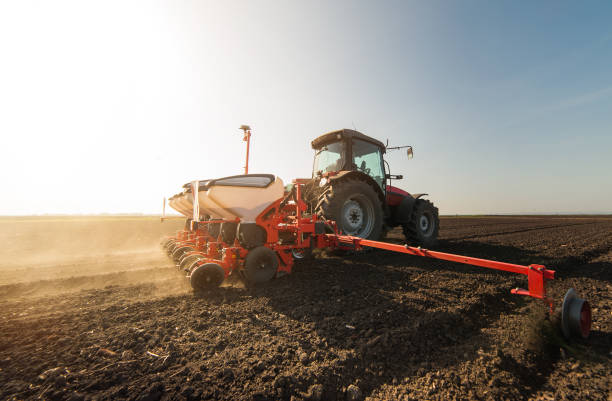 istock Farmer with tractor seeding - sowing crops at agricultural fields in spring 947158170
