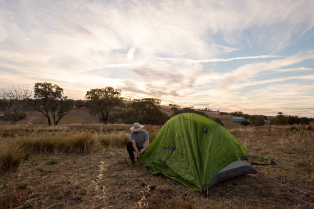 istock Camping man sets up his tent in the yellow afternoon light 947171286