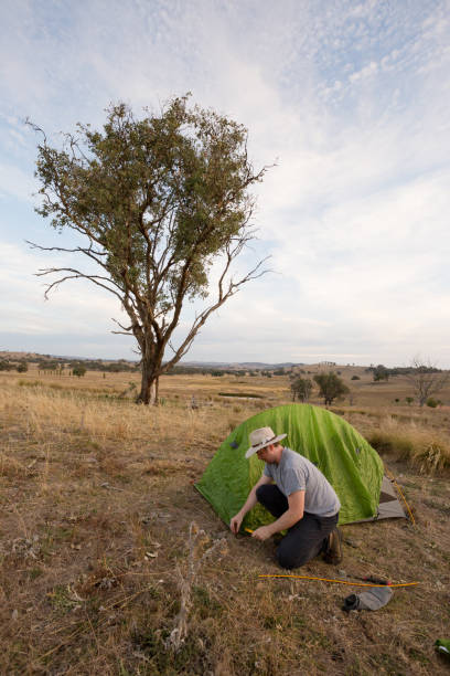 istock Camping man hammers his tent peg into hard ground 947171290