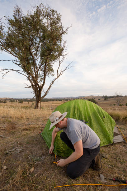 istock Camping man hammers his tent peg into hard ground 947171312