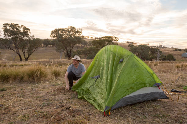 istock Camping man sets up his tent in the yellow afternoon light 947171326