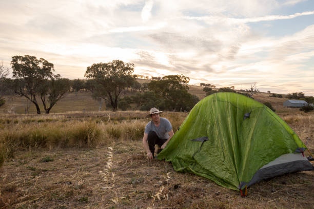 istock Camping man sets up his tent in the yellow afternoon light 947171356