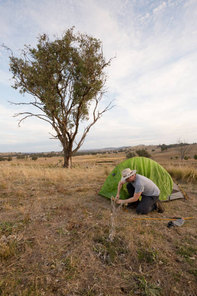 istock Camping man hammers his tent peg into hard ground 947171370