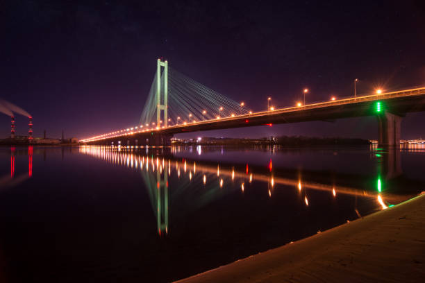 istock Night city. Beautiful glowing bridge over the river 947177920
