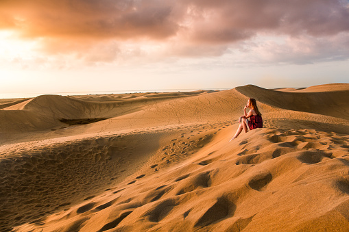 A young woman is walking in the sand dunes