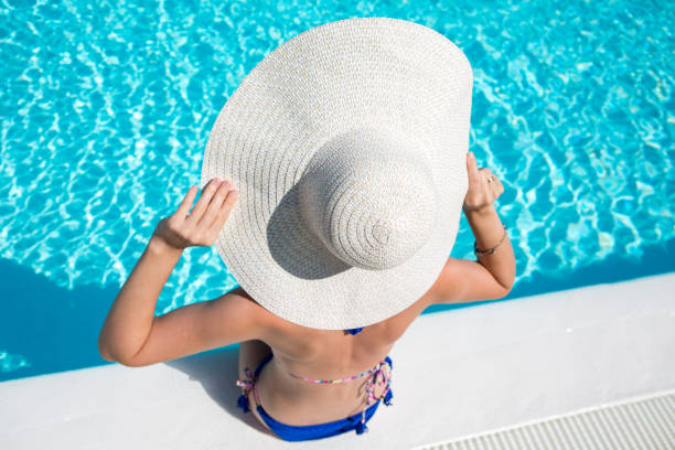 istock Young woman sits at the pool edge 947185800