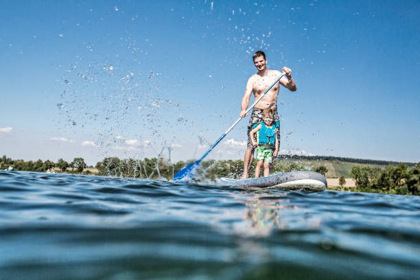 Full Length Of Shirtless Man With Son Paddleboarding On River Against Sky Photo Taken In Neckarsulm, Germany heilbronn stock pictures, royalty-free photos & images