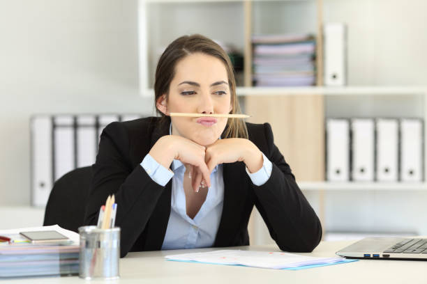 Lazy employee wasting time at office Lazy employee wasting time playing with a pencil at office melancholy computer support specialist stock pictures, royalty-free photos & images