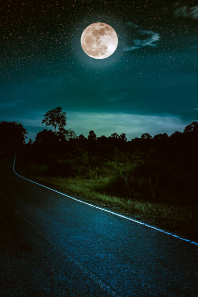 istock Dark sky with full moon and roadway through suburban zone. 947193420