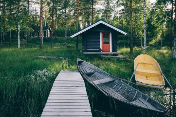 伝統的な木造の小屋。湖と釣り船を桟橋にフィンランド式サウナ - scandinavian lake cottage house ストックフォトと画像