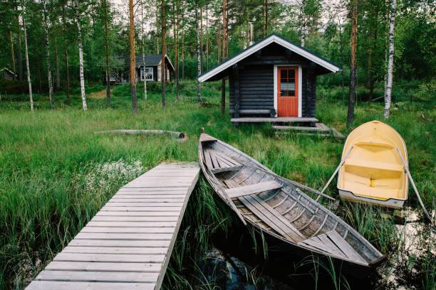 traditional wooden hut. finnish sauna on the lake and pier with fishing boats - fishing hut imagens e fotografias de stock