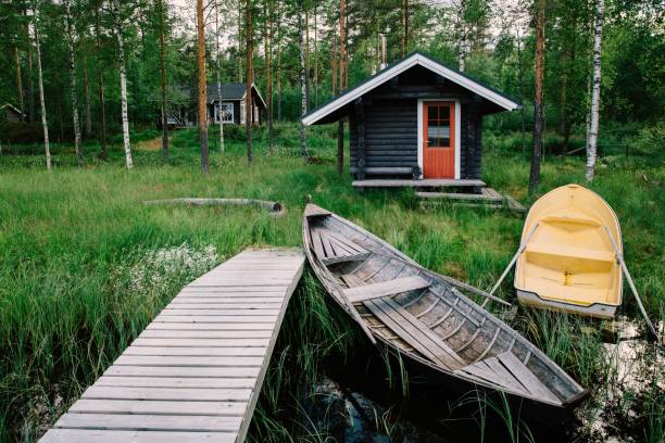 традиционная деревянная хижина. финская сауна на озере и пирс с рыбацкими лодками - fishing hut стоковые фото и изображения