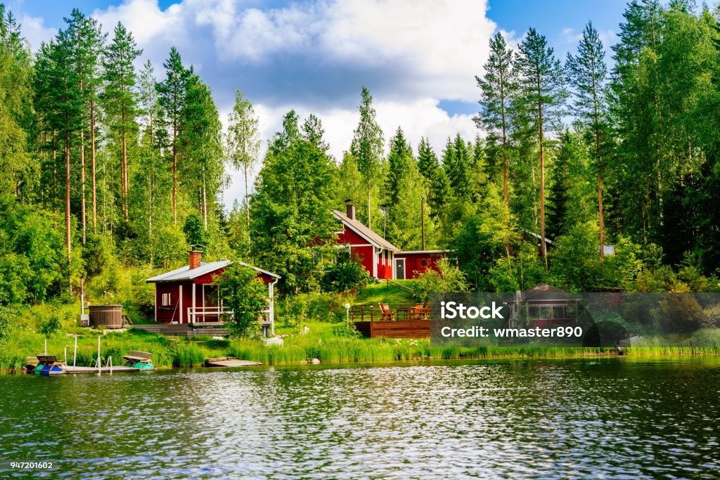 A traditional Finnish wooden cottage with a sauna and a barn on the lake shore. Summer rural Finland. A traditional Finnish wooden cottage with a sauna and a barn on the lake shore. Summer landscape. Rural Finland. Finland Stock Photo