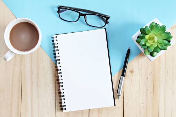 istock Top view or flat lay of open notebook with blank pages and coffee cup on office table 947202812
