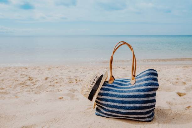 Blue beach bag with hat on the sandy beach with the blue sky background Blue beach bag with hat on the sandy beach with the blue sky background summer holiday beach bag stock pictures, royalty-free photos & images