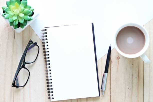 istock Top view or flat lay of open notebook with blank pages and coffee cup on office table 947205954