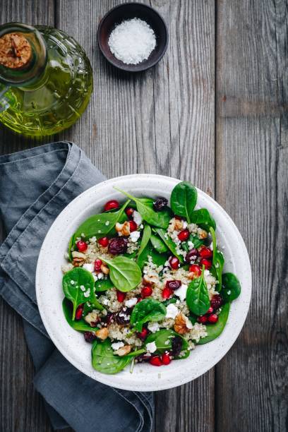 istock Green salad spinach bowl with quinoa, pomegranate, walnuts, goat cheese and dried cranberries. 947206066