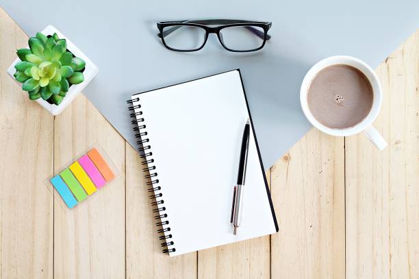 istock Top view or flat lay of open notebook with blank pages and coffee cup on office table 947206428