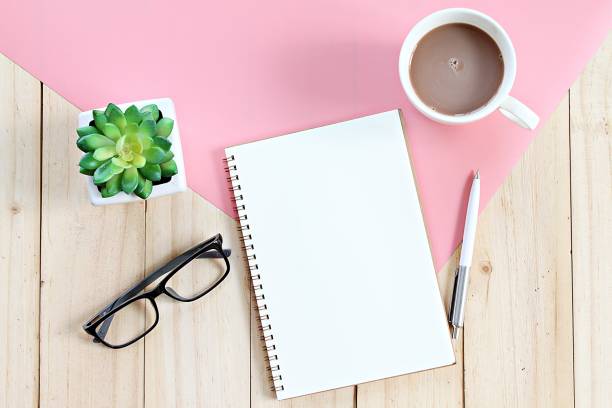 istock Top view or flat lay of open notebook with blank pages and coffee cup on office table 947206460