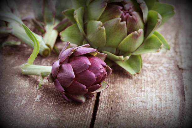 istock purple artichokes on rustic wooden background 947207140