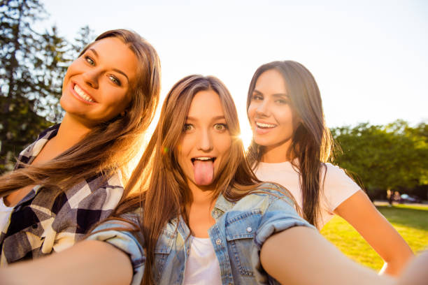 istock Three happy girls having fun and making comic selfie with tongue 947213004