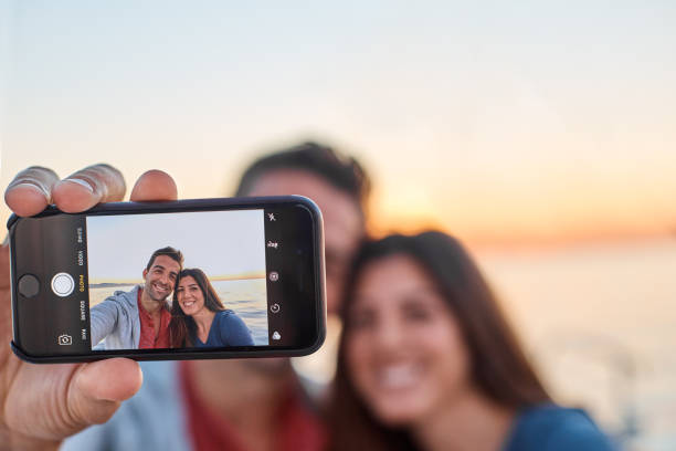 Guess where we're having our holiday Shot of a young couple taking a selfie together on an ocean cruise yacht selfie stock pictures, royalty-free photos & images