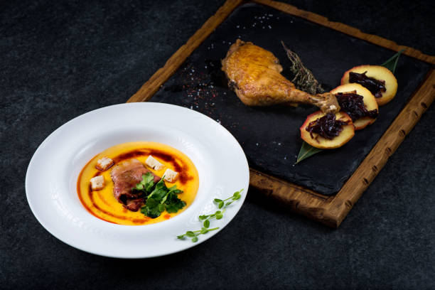 istock An appetizing pumpkin soup is served in a white plate in a restaurant. Duck confit with baked apple 947215980