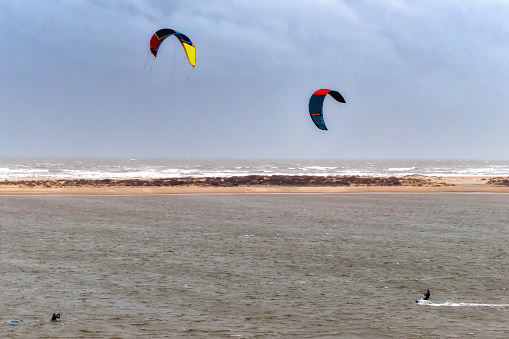 Unidentified surfers practice surf parasailing in the Atlantic coast in Nuevo Portil, Andalusia, Spain.