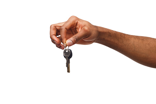 Black male hand holding key to house, car or business, motivation poster isolated on white background, copy space
