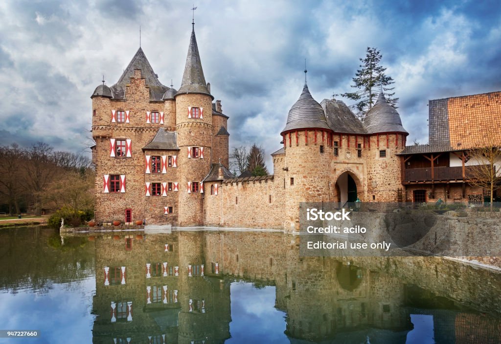 Moated castle Satzvey, Germany Mechernich, Germany - April 08, 2018: View of the water castle Satzvey with dramatic clouds, watersurface with reflections in the foreground. Castle Stock Photo