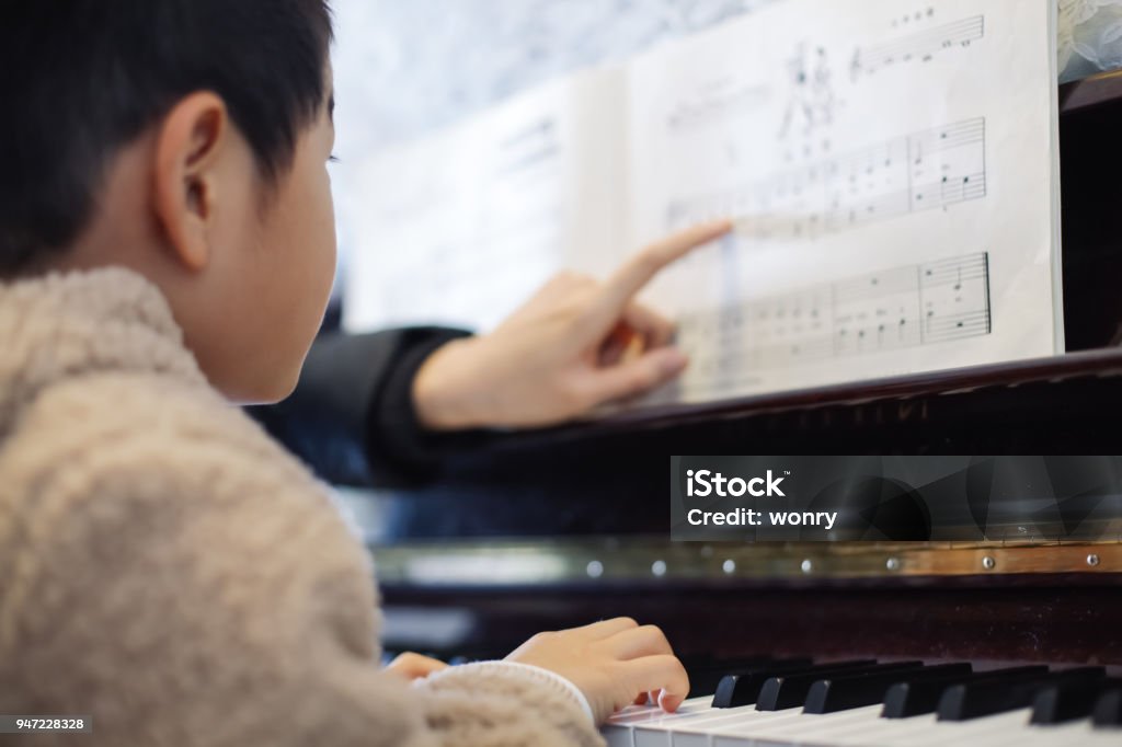 Young boy learning to play piano Piano Stock Photo