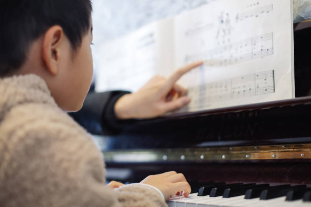 Young boy learning to play piano stock photo
