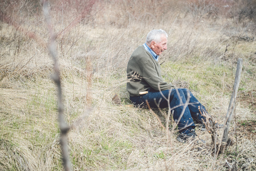 Old man from eastern europe in his eighties taking a break from tending his orchard
