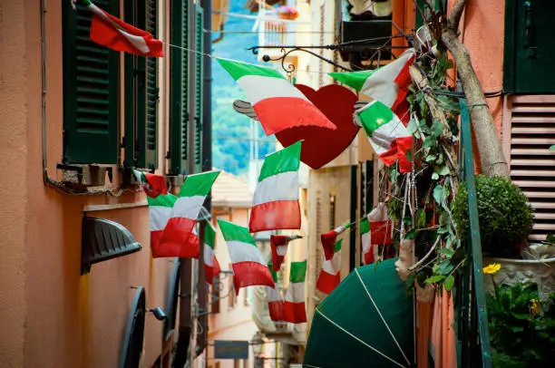 narrow street scene filled with italian flags on both sides.