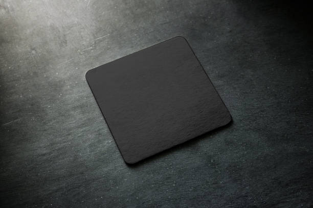 Blank black beer coaster mockup lying on grey desk Blank black beer coaster mockup lying on grey desk. Square clear dark bar cork table-mat design mock up top side view. Quadrate cup or bottle rug display, isolated. above can drink high angle view stock pictures, royalty-free photos & images