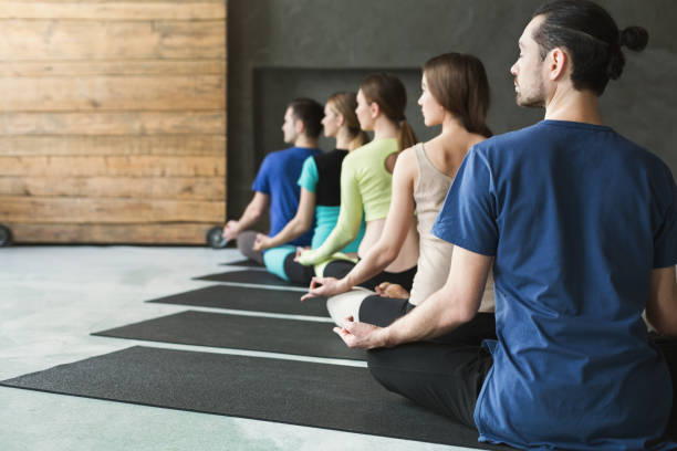 istock Young women and men in yoga class, relax meditation pose 947237290