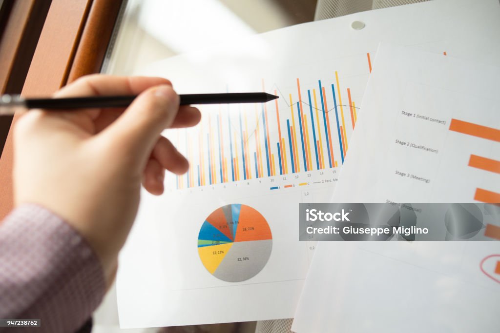 Male hand pointing with a pencil at a sales funnel chart during a business meeting in office Male hand pointing with a pencil at a sales funnel chart or sales pipeline during a business meeting in office. Concept of marketing strategy Adult Stock Photo