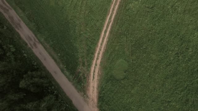 Flying over country road in green field