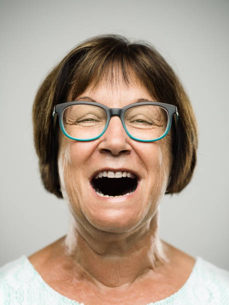 Real shouting senior woman portrait Close up portrait of hispanic mature woman with shouting expression against white background. Vertical shot of real senior woman screaming in studio. Short brown hair and modern glasses. Photography from a DSLR camera. Sharp focus on eyes. mouth open human face shouting screaming stock pictures, royalty-free photos & images