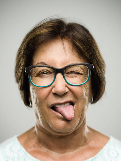 retrato de mujer real senior sacando la lengua - sneering grimacing women human face fotografías e imágenes de stock