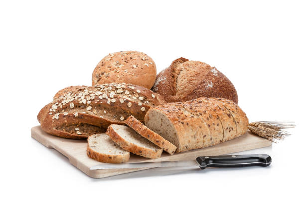 istock Loaves of bread on a cutting board isolated on white background 947253638