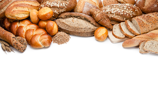 Top view of a collection of different types of bread placed at the top of a white background making a frame and leaving useful copy space for text and/or logo. Predominant colors are brown and white. High key DSRL studio photo taken with Canon EOS 5D Mk II and Canon EF 70-200mm f/2.8L IS II USM Telephoto Zoom Lens